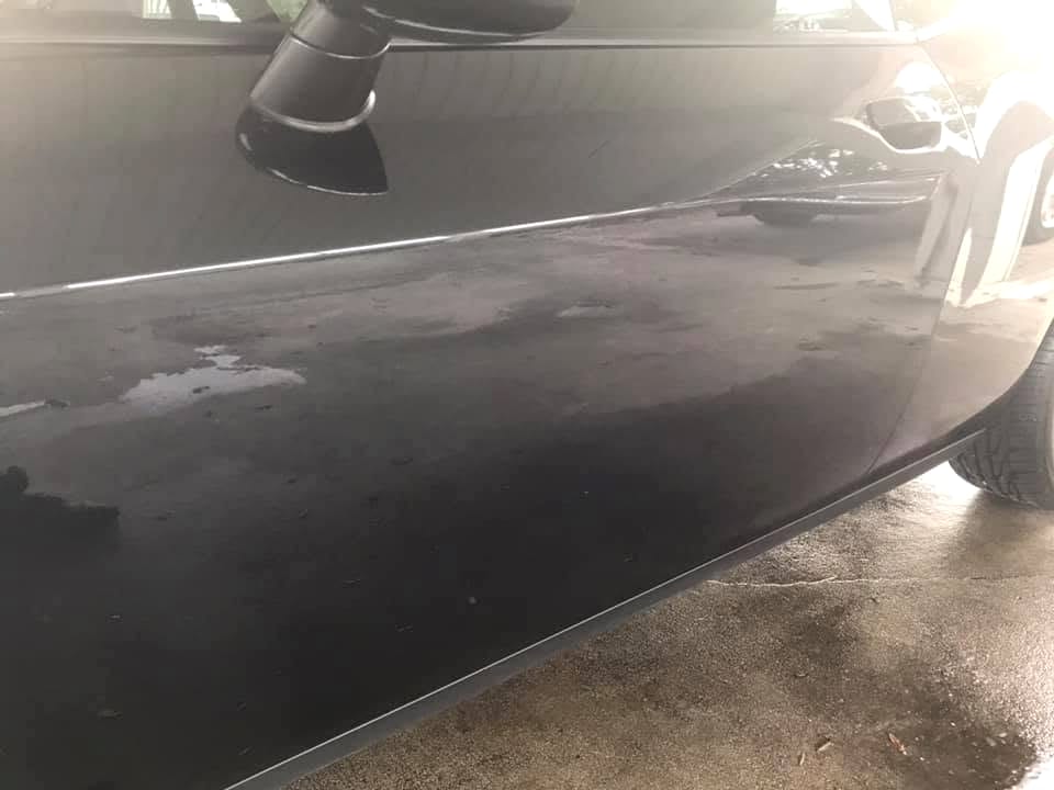 Water beading off a freshly ceramic-coated black car panel, showing the hydrophobic finish