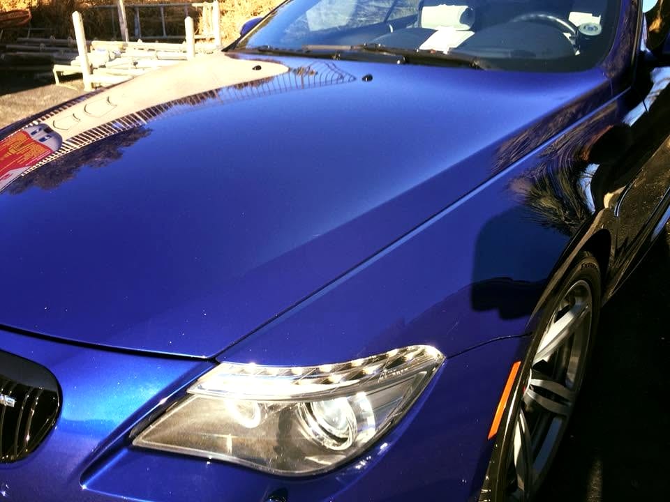 Corrected blue car hood and headlight showing a flawless, swirl-free gloss